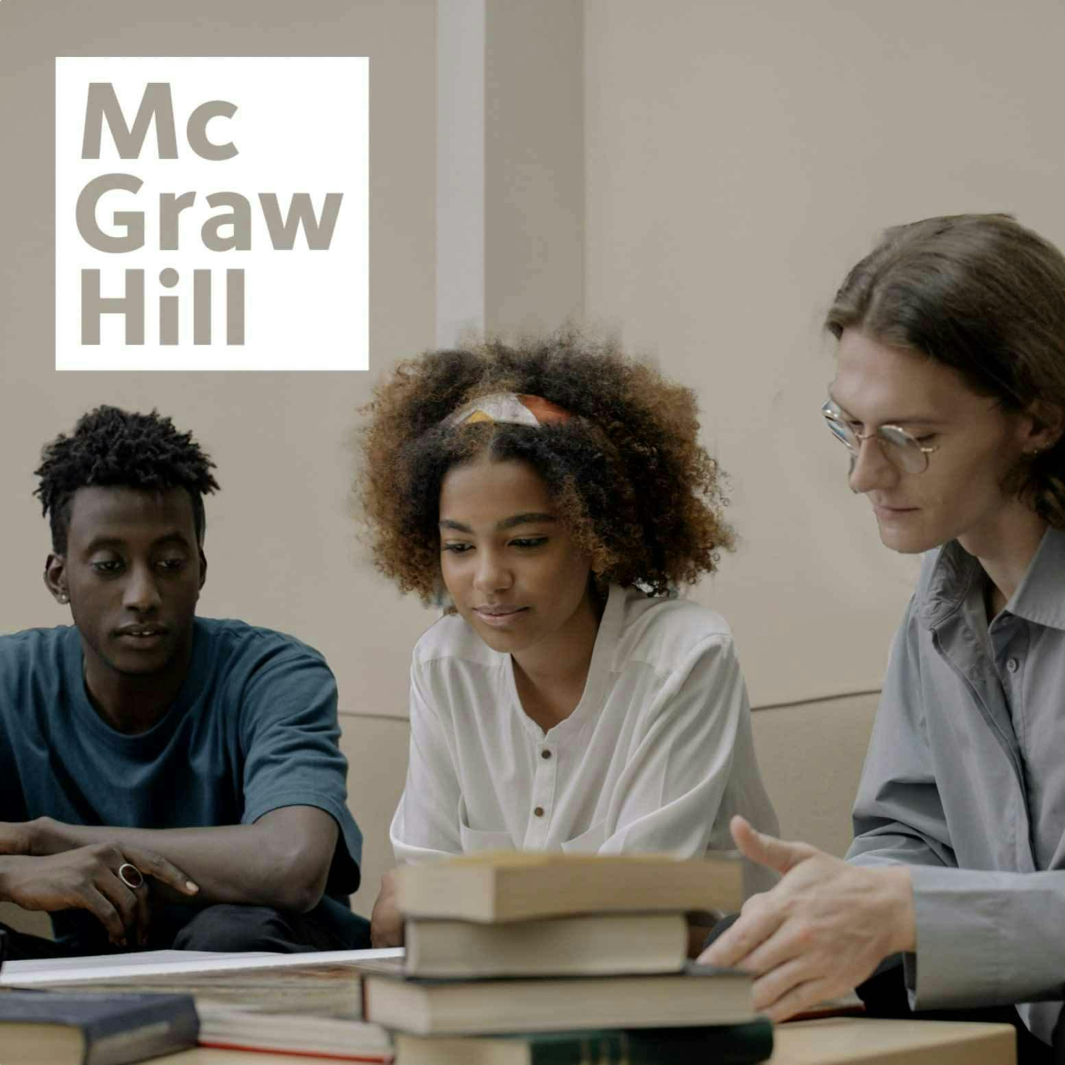 Three students all leaning over a set of books studying together with a white McGraw Hill logo in the top left corner